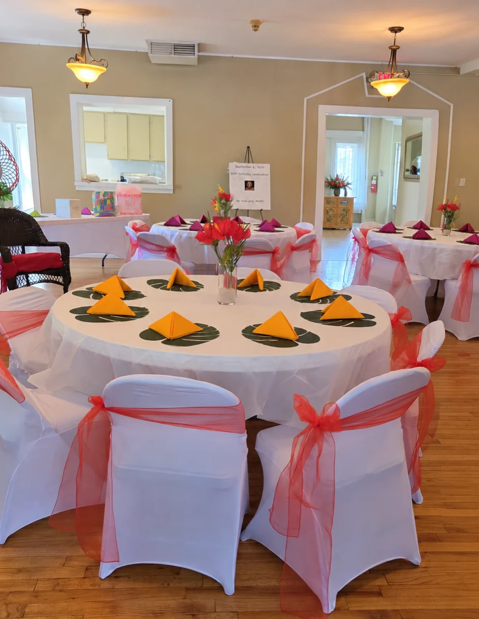 Banquet hall of round tables with white spandex chair covers tied with red organza sashes